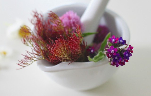 Various flowers and white pestle inside a white mortar