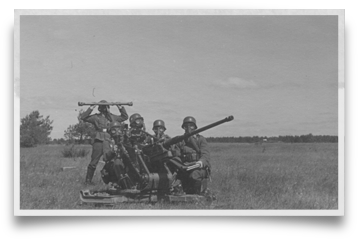 Photograph of a 2cm Flak gun and crew in gas masks.